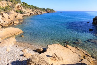 Temiz ve sakin suları olan engebeli bir sahil.