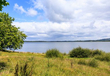 Pofuduk bulutlarla dolu güneşli bir günde, Galiçya 'daki Fervenza rezervuarının iki kıyısına bakın.