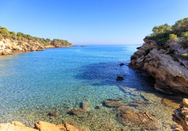 Güneş ışınları, İspanya 'nın Tarragona kentindeki Costa Dorada' daki bu küçük körfezin berrak sularını aydınlatır..