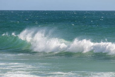 Deniz turkuvaz tacı öne doğru eğilir, uçsuz bucaksız kumla birleşen bir köpük öpücüğü.
