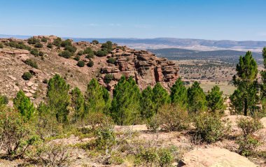 Teruels kayalık dağ oluşumları geniş bir vadiye bakan ormanlar ve uzak dağ siluetleri