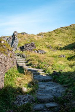 Stone path at Djpalnssandur black sand beach on a sunny day, Iceland