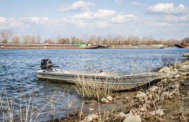İlkbaharda Tuna Nehri 'nin panoramik manzarası. Baharda Tuna nehrinin kıyısına demirlemiş ahşap bir balıkçı teknesinin manzarası.