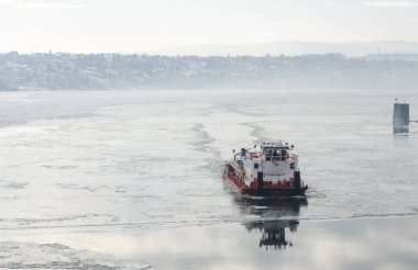 Kar ve buzla kaplı Tuna Nehri. Petrovaradin Kalesi, Voyvodina, Novi Sad, Petrovaradin, Sırbistan 'ın aşağısındaki Tuna Nehri' nin donmuş ve karla kaplı su yolunda buzkıran bir gemi.