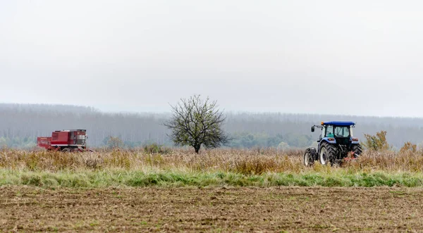 겨울에 질하여 옥수수의 잔존물을 준비가 밭에서 수확자와 커다란 푸른색 트랙터 — 스톡 사진