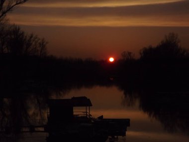 Tuna Nehri 'nin durgun sularında sonbahar günbatımının panoramik bir görüntüsü. Günün sonbaharında Tuna Nehri 'nin durgun sularının panoramik görüntüsü.