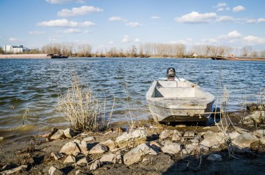 İlkbaharda Tuna Nehri 'nin panoramik manzarası. Baharda Tuna nehrinin kıyısına demirlemiş ahşap bir balıkçı teknesinin manzarası.