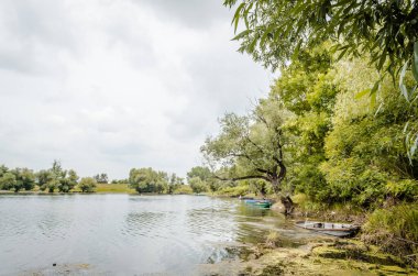 Kıyıya bağlı ahşap balıkçı tekneleri. Sonbaharda gölün kıyısına demirlemiş küçük ahşap balıkçı tekneleri manzarası..
