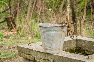Novi Sad 'ın banliyölerindeki eski kuyunun beton kaplamasında metal kova.