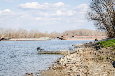 İlkbaharda Tuna Nehri 'nin panoramik manzarası. Baharda Tuna nehrinin kıyısına demirlemiş ahşap bir balıkçı teknesinin manzarası.