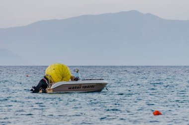 Yunanistan 'ın Pefkochori plajının yanındaki su yüzeyinde demirli kırmızı ve beyaz sürat teknesi.