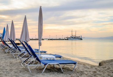 Şemsiyeli sahil manzarası ve şemsiyeli sahilin manzarası ve küçük Pefkochori kasabasında güneşlenmeler. Sabahları küçük Pefkochori kasabasında şezlonglar..