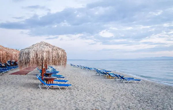 Sabahları küçük Pefkochori kasabasında güneşli ve güneşli plaj manzarası..