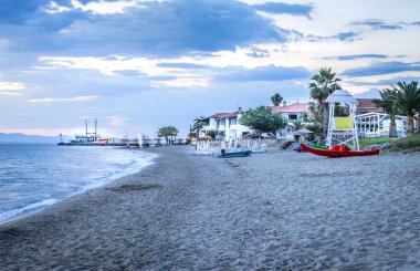 View of the beach with parasols and sun loungers in the small town of Pefkochori, in the morning.