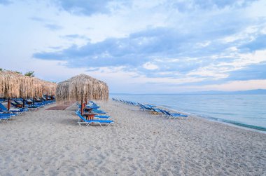 View of the beach with parasols and sun loungers in the small town of Pefkochori, in the morning.