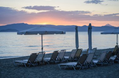 View of the beach with parasols and sun loungers in the small town of Pefkochori, in the morning.