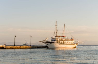 Anchored tourist boat by the waterfront in Pefkochori, Greece. An anchored tourist boat in the afternoon, tied to the shore in Pefkohori, Greece.