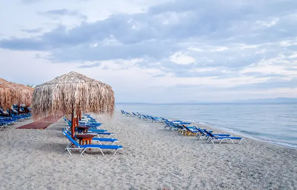View of the beach with parasols and sun loungers in the small town of Pefkochori, in the morning.