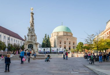Pecs, Hungary - October 06, 2018: Obeliskl - Monument St. Trinity in Pecs in front of Mosque Qazim in the Main Square in Pecs Hungary.