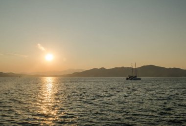 Evia Adası, Yunanistan - 01 Temmuz. 2020: Yunanistan 'ın Evia adasında günbatımı. Yunanistan 'ın Ege Denizi' ndeki Evia adasında günbatımının panoramik görüntüsü. Evia Yunanistan adasındaki sakin Ege Denizi 'nde güzel bir gün batımı