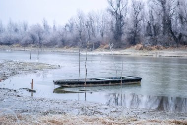 Tuna Nehri 'nin kıyısında donmuş suda demirli ahşap bir balıkçı teknesi..