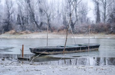 Tuna Nehri 'nin kıyısında donmuş suda demirli ahşap bir balıkçı teknesi..