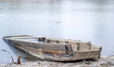 Tuna Nehri 'nin kıyısında donmuş suda demirli ahşap bir balıkçı teknesi..