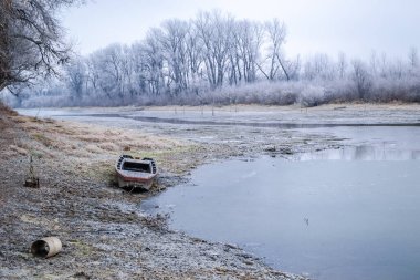 Tuna Nehri 'nin kıyısında donmuş suda demirli ahşap bir balıkçı teknesi..