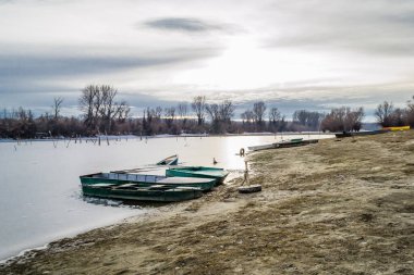 Tahta tekneler gölün donmuş sularında unutuldu..
