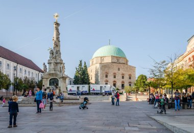 Pecs, Hungary - October 06, 2018: Obeliskl - Monument St. Trinity in Pecs in front of Mosque Qazim in the Main Square in Pecs Hungary.