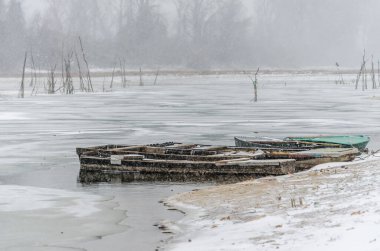 Tuna Nehri 'nin kıyısında donmuş suda demirli ahşap bir balıkçı teknesi..
