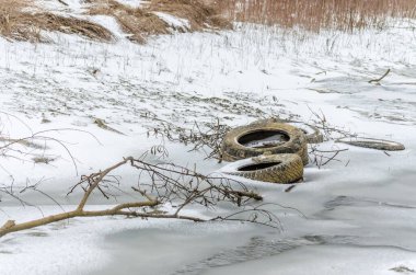 Terk edilmiş araba lastikleri kışın koruma altında tutulur, karla kaplıdır..