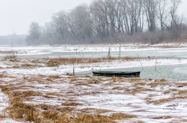 Tuna Nehri 'nin kıyısında donmuş suda demirli ahşap bir balıkçı teknesi..