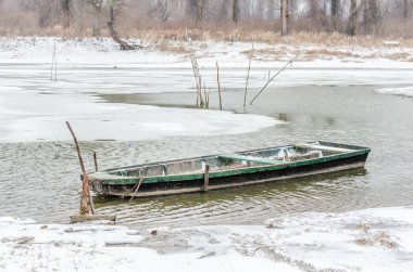 Tuna Nehri 'nin kıyısında donmuş suda demirli ahşap bir balıkçı teknesi..