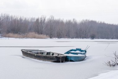 Tuna Nehri 'nin kıyısında donmuş suda demirli ahşap bir balıkçı teknesi..