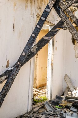 The remains of the burnt house. Ruined and collapsed house burnt and damaged in the fire with remains of the wooden reinforcement poles of roof selective focus. Burned house