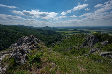 Lookout with a rock in the foreground of green leafy forests and hills in the Slovak Little Carpathian Mountains