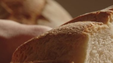 Close up view of person slicing fresh bread with knife. Cutting crusty bread in the kitchen for dinner. High quality 4k footage