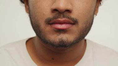 Cropped view of a bearded young man smiling to camera. Studio footage of excited guy expressing positive emotions on white background. High quality 4k footage