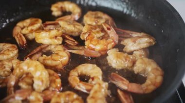Delicious shrimps frying in oil. Slow motion video of seafood cooking process. Close up view of prawns fried in the pan. High quality FullHD footage