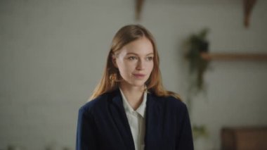 Beautiful girl in jacket looking to camera with gently smile. Indoor footage of a pretty young woman posing at home . High quality 4k footage