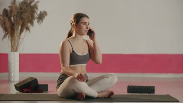 Laughing Girl Sitting Fitness Mat Cross Legged Talking Phone Smiling — Stockvideo