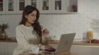 The businesswoman sits down at her desk and rests her head on her hand for a moment to consider her response to the employer, and then starts typing. Remote work from home. High quality 4k footage