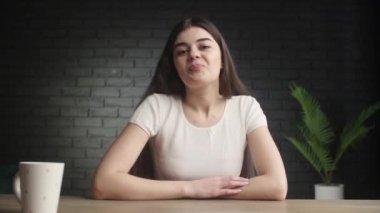 Smiling blogger waving hello while recording her vlog. A positive brunette girl waves her hand at the camera and answers questions. Online influencer. High quality 4k footage