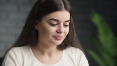 Brunette young woman waving hello to camera during online conference. Beautiful freelancer girl happily greets her employer via video call and listening. High quality 4k footage