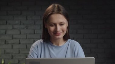 Bilgisayarın başında çalışırken gülümsemeye başlayan bir kızla video. Esmer bir kadın stüdyoda otururken uzaktan çalışıyor. Yüksek kalite 4k görüntü