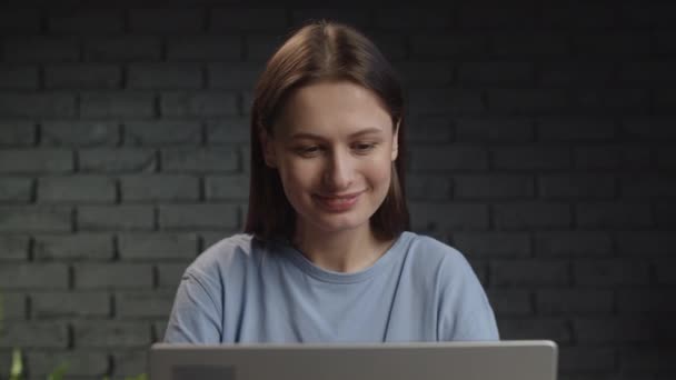 和一个在电脑前工作时开始笑的女孩的视频 一个黑发女人坐在演播室里做远程工作 高质量的4K镜头 — 图库视频影像