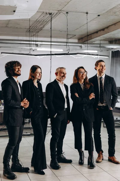 Full-length view of international business team. Multiethnic group of coworkers standing in office with smile. High quality photo