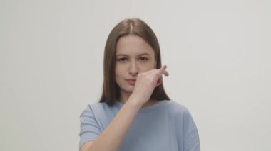 A brunette imitating closing her mouth and throwing away a key. The young woman promises to keep a secret. High quality 4k footage