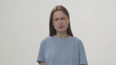 Video of an annoyed woman looking at the camera and shrugging her shoulders. Close-up studio shot. High quality 4k footage